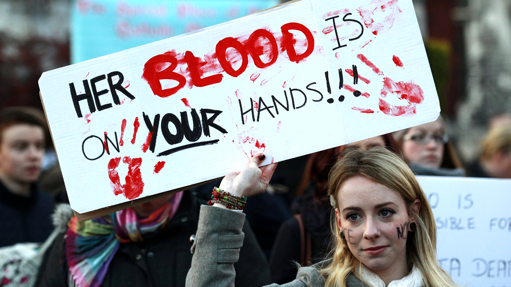 A woman holds a poster during a vigil in Dublin on 17 November in memory of Savita Halappanavar and in support of changes to abortion law. (R)