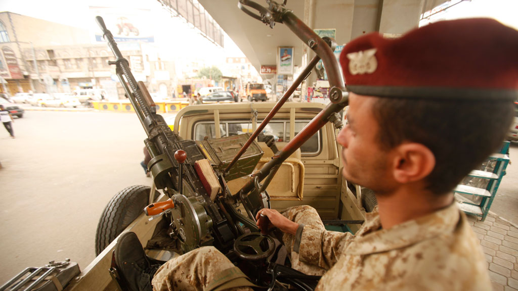 An army trooper sits beside a machinegun that is mounted on a patrol vehicle at at checkpoint in Sanaa (R)