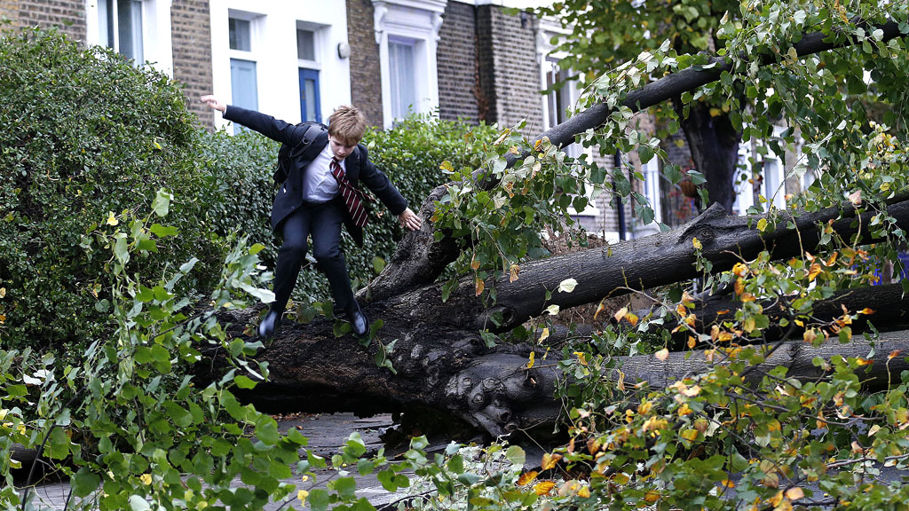 Theo Harcourt, 13, jumps over a fallen tree as he makes his way to school in Islington, north London