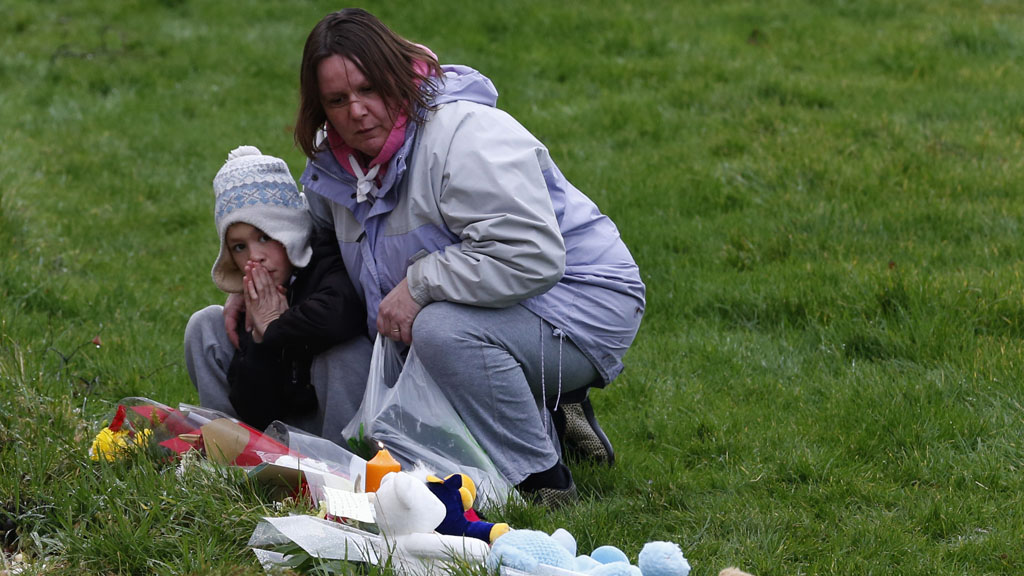 People look at floral tributes and soft toys left near the home of three-year-old Mikaeel Kular, in Edinburgh, Scotland January 18, 2014.