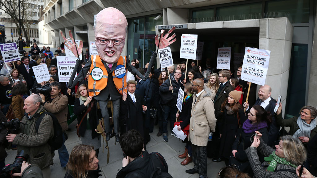 Above: Barristers and solicitors carry on effigy of Chris Grayling as they protest against legal aid cuts in March (picture: Getty)