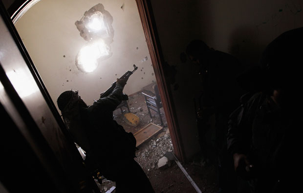 A Libyan rebel fighter quickly rounds a corner and fires on trapped government loyalist troops a few meters away during house-to-house fighting in downtown Misrata April 20 (Getty)
