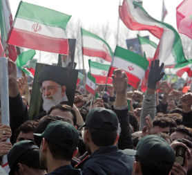 Basij forces stand as Iranians hold up a portraits of Supreme leader Ayatollah Ali Khamenei. (Getty)