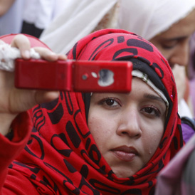 Woman using her phone to document a protest at Cairo University (Getty)