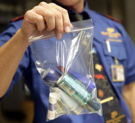 A security officer shows a plastic bag which contains a passenger's liquid belongings. (Getty)