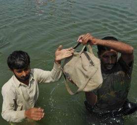 Pakistan flood survivors are assisted by a Pakistani Navy official as they wade through floodwaters in Khairpur Nathan Shah. (Getty)