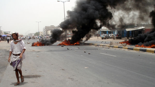 Yemeni man walks past burning tyres during a protest in the southern town of Sabr. (Getty)