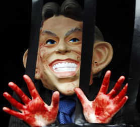 A demonstrator wearing a mask of Britain's former Prime Minister Blair, waves red stained hands. (Reuters)